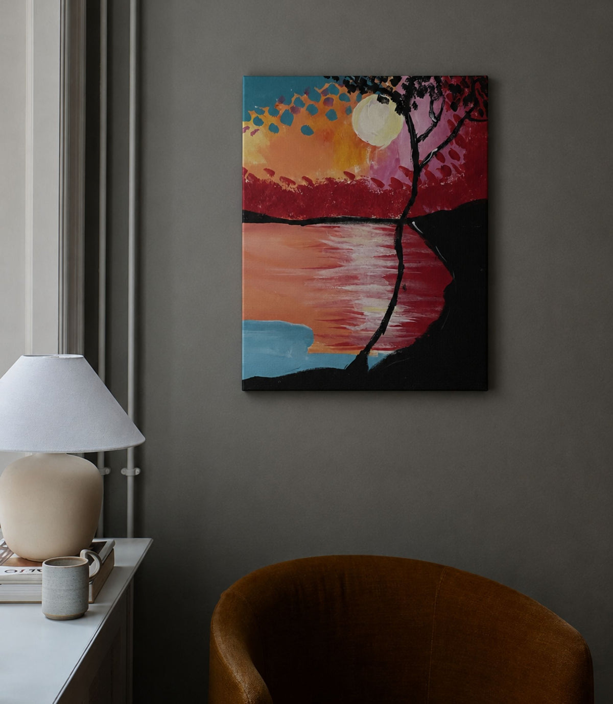 Sunset lake and silhouetted tree canvas displayed in a modern interior